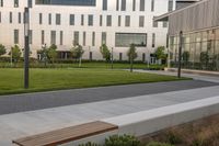 a city street surrounded by grass and tall buildings at the end of a street there is a paved pathway in front of the building