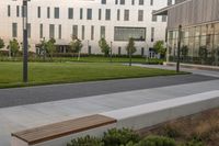 a city street surrounded by grass and tall buildings at the end of a street there is a paved pathway in front of the building