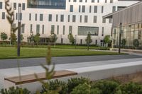 a city street surrounded by grass and tall buildings at the end of a street there is a paved pathway in front of the building