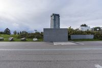 an empty parking lot near a tall building with a sign at the front in a city