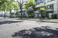 a street is lined with trees in front of apartment buildings at the end of a sidewalk