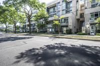 a street is lined with trees in front of apartment buildings at the end of a sidewalk