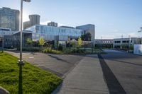 a city street surrounded by grass and tall buildings at the end of a street there is a paved pathway in front of the building