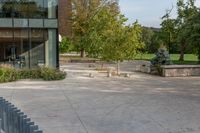 two trees sitting outside of a large building with a fenced off area in front