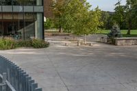 two trees sitting outside of a large building with a fenced off area in front