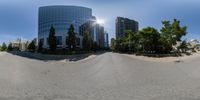 a wide view of some tall buildings along a quiet road with trees and bushes in front