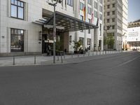 a bus stop has two signs on it on the road outside a building in europe