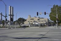 an empty street is near some factory smoke stacks and stop lights with a car coming to the top of it