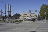 an empty street is near some factory smoke stacks and stop lights with a car coming to the top of it
