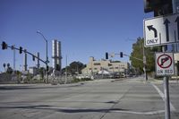 an empty street is near some factory smoke stacks and stop lights with a car coming to the top of it