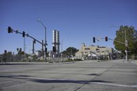 an empty street is near some factory smoke stacks and stop lights with a car coming to the top of it
