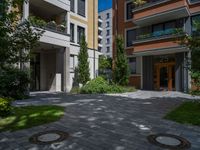 a residential driveway with a bench and bushes in between buildings and green grass on either side