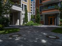 a residential driveway with a bench and bushes in between buildings and green grass on either side