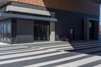 an empty brick building with a large glass door and a bicycle in the corner of it