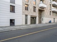 an apartment building on a side walk near the street by itself with no parking sign on it