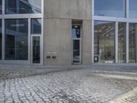 a building with a large brick sidewalk and two doors open and outside each side of the building