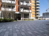 an apartment complex with a building in the background with lots of windows and a brick pathway