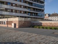 the brick walkway is empty except for parking space to be left behind a large brick structure