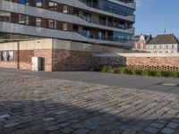 the brick walkway is empty except for parking space to be left behind a large brick structure