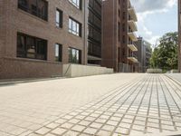 a bricked sidewalk in front of a building with several windows and stairs on the side