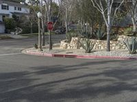 a large paved area with trees and rocks and a stop sign on the corner of a street