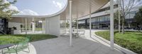 patio seating and large open area of building on grassed courtyard with outdoor space and trees in foreground