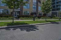 there are two parking meters standing next to each other on the sidewalk, along with a large apartment building and lawn