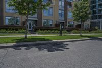 there are two parking meters standing next to each other on the sidewalk, along with a large apartment building and lawn