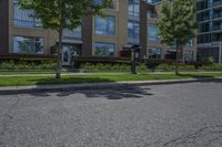 there are two parking meters standing next to each other on the sidewalk, along with a large apartment building and lawn