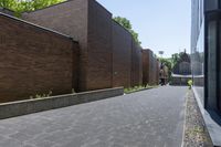 a brick walkway outside a building and two empty benches beside it on the side of a sidewalk