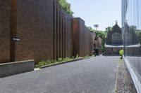 a brick walkway outside a building and two empty benches beside it on the side of a sidewalk