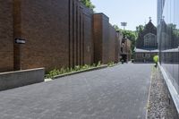 a brick walkway outside a building and two empty benches beside it on the side of a sidewalk