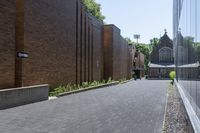 a brick walkway outside a building and two empty benches beside it on the side of a sidewalk