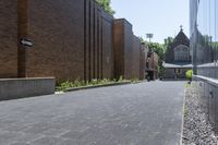 a brick walkway outside a building and two empty benches beside it on the side of a sidewalk