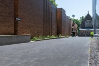 a brick walkway outside a building and two empty benches beside it on the side of a sidewalk