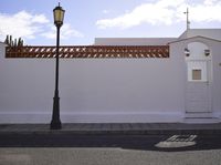 a tall lamp post on the side of a street corner with a building behind it