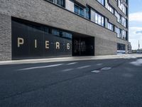 the entrance of pier 64 is clear and empty during the day in this photograph, taken from the side of the street