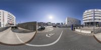 a fisheye view shows cars going by on an empty street on the outskirts of a large building