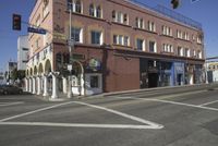 a car on the street near a building and traffic lights in front of it and a red brick building with many windows