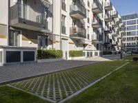 the grassy area next to a walkway and many balconies in an apartment building