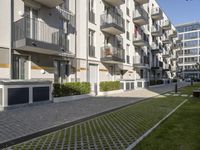 the grassy area next to a walkway and many balconies in an apartment building