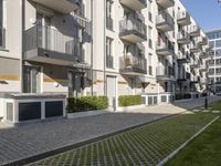 the grassy area next to a walkway and many balconies in an apartment building