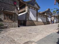 people are walking down the street in china looking at the old stone buildings of the village