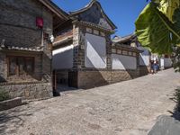 people are walking down the street in china looking at the old stone buildings of the village