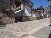 people are walking down the street in china looking at the old stone buildings of the village