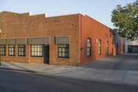 a red building with white trim and windows is on the side of a street with black shutters