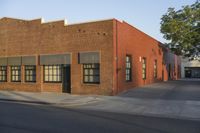 a red building with white trim and windows is on the side of a street with black shutters