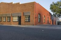 a red building with white trim and windows is on the side of a street with black shutters