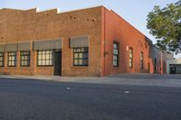 a red building with white trim and windows is on the side of a street with black shutters