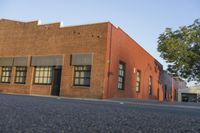 a red building with white trim and windows is on the side of a street with black shutters